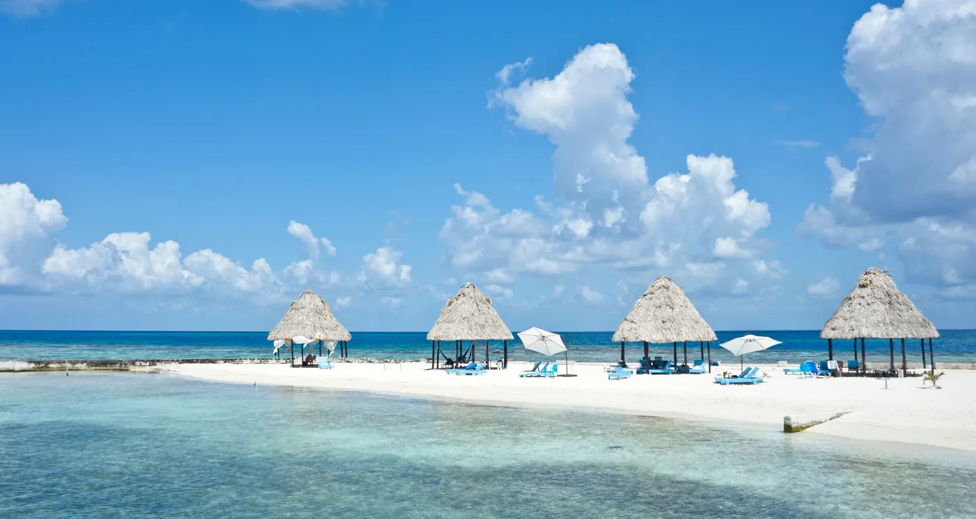 Thatched palapas and white sand on a small caye off Ambergris Caye, Belize, surrounded by clear turquoise water